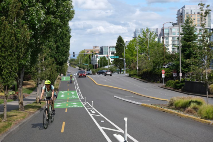 Looking down NE 12th Street with a rendering of a cycletrack with painted lines, green painted boxes and flexible posts.