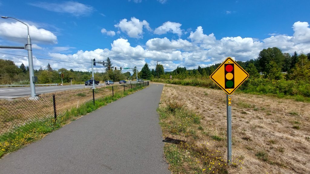 A partly cloudy but bright day on the Centennial Trail with a sign noting a street crossing.