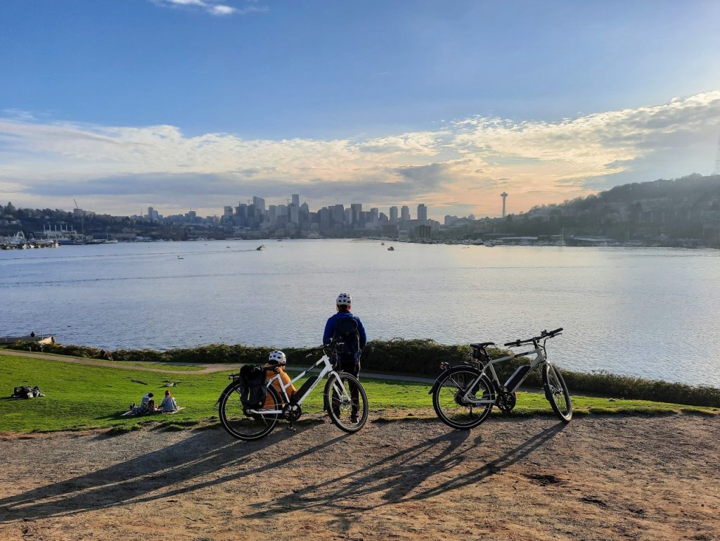 Two women park their e-bikes and take in the iconic Lake Union and skyline view from the top of Gas Works