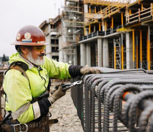 Sound Transit Prepares to Hire Three Megaproject Czars and Implement Other Expert Advice A construction works cuts rebar with the elevated station structure in the background.