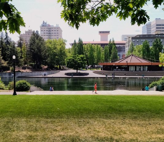 The Housing Crisis Isn’t Limited to Greater Seattle People stroll and jog in Waterfront Park with the Spokane skyline in the background.