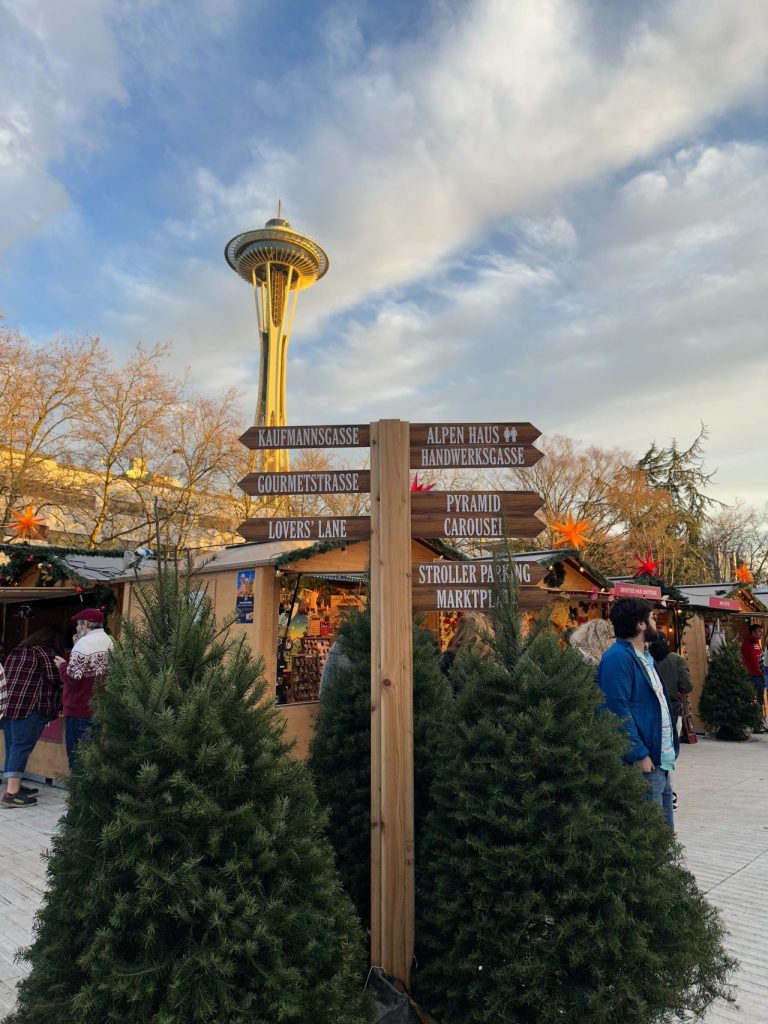 Christmas trees border the sign and the Space Needle is in the background.