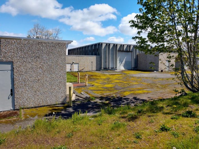 Fort Lawton include patchy grass and drab concrete low slung buildings and garages that used to serve the military installation.