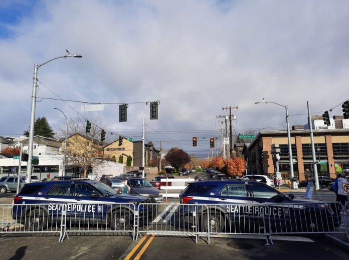 Two police SUVs are parked behind metal barricades blocking traffic from Market Street.