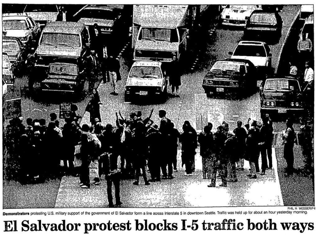 The headline reads "El Salvador protesters block I-5 traffic both ways." The caption notes they objected to the U.S. government's support of the government of El Salvador and blocked traffic for about an hour the previous morning.