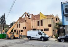 Franz: Mobilize Washington State-Owned Land to Tackle Housing Affordability Crisis A small crane move materials to the top of a three story townhome complex where a construction work receives them.