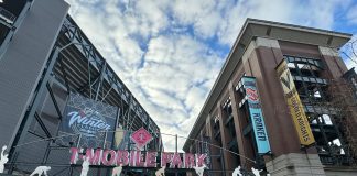 The NHL Winter Classic Can Accelerate Seattle’s Sonics Boom Entrance gate to T-Mobile Park with crowd going through ticketing, looking upward towards soft clouds and banners for Vegas and Seattle.