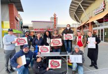 Voters Set to Decide on Raise The Wage Renton in February Ballot Measure A group of about 15 campaign volunteers hold clip board and campaign signs at a mall plaza.