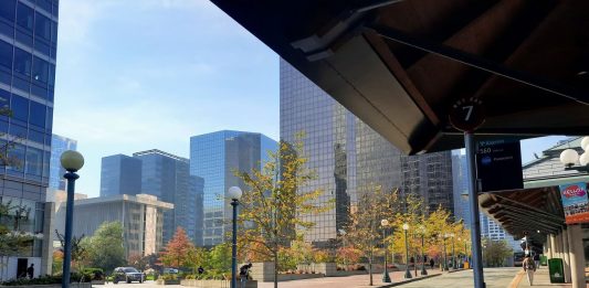 A canopy shelters the Bellevue Transit Center with downtown office towers in the background.