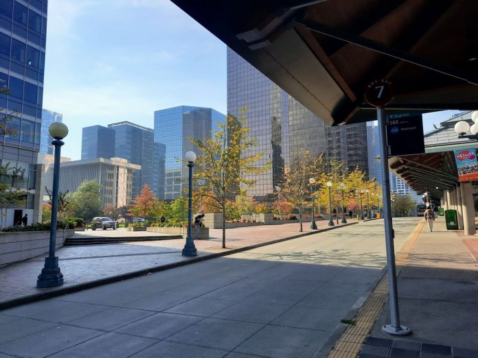 A canopy shelters the Bellevue Transit Center with downtown office towers in the background.