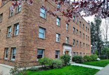 More than Zoning Reform: Home in Tacoma and the Prospect of Real Change A four-story historic brick apartment building with a blossoming tree out front.