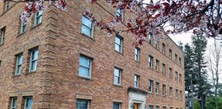 More than Zoning Reform: Home in Tacoma and the Prospect of Real Change A four-story historic brick apartment building with a blossoming tree out front.