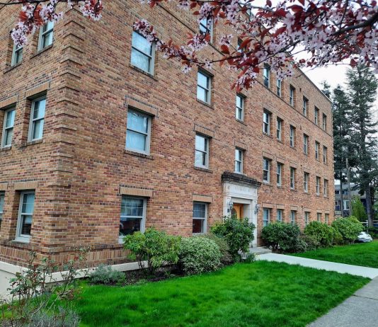 More than Zoning Reform: Home in Tacoma and the Prospect of Real Change A four-story historic brick apartment building with a blossoming tree out front.