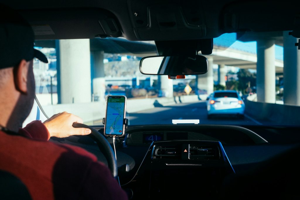 The backseat view with a gig driver looking out the windshield going under an overpass.