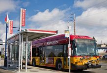 Metro Starts Federal Way Link Bus Restructure Planning A red and gold RapidRIde bus waits an a bus shelter with the sign indicating it's headed to Federal Way Transit Center.