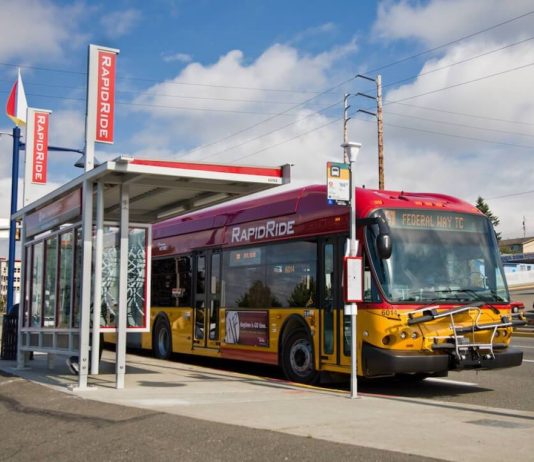 Metro Starts Federal Way Link Bus Restructure Planning A red and gold RapidRIde bus waits an a bus shelter with the sign indicating it's headed to Federal Way Transit Center.