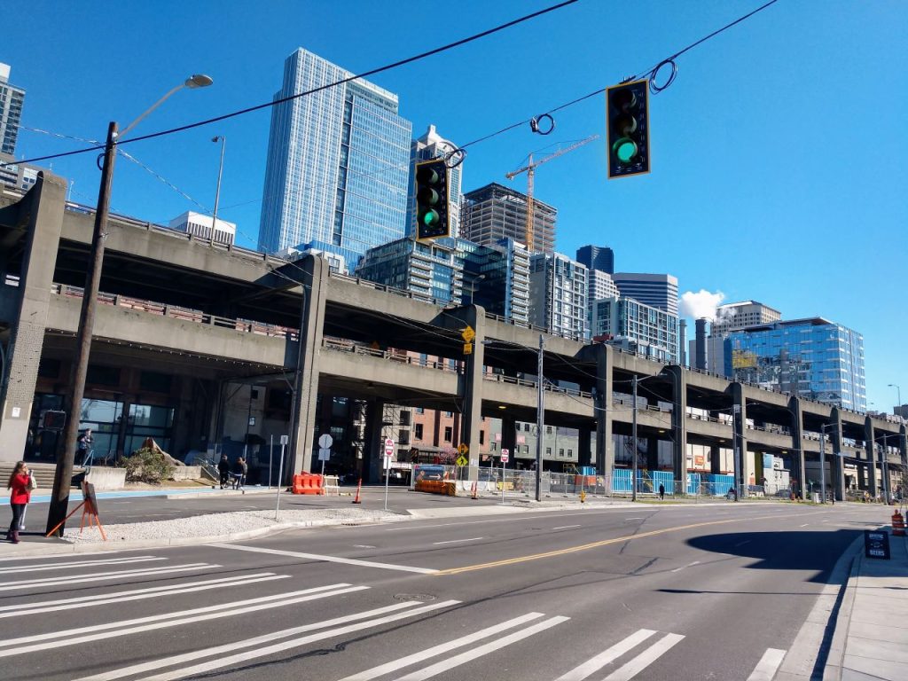 Two levels of elevated highway rise above a surface road below in a concrete monstrosity, obscuring the bottom half of the downtown Seattle skyline from the waterfront.