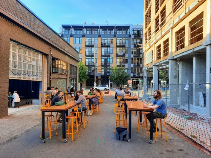 The back patio at Stoup with Ryan Packer sitting at one of the table and apartment buildings in the background.