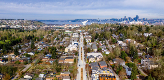 An aerial photo of a boulevard with port cranes and Elliott Bay in the distance.