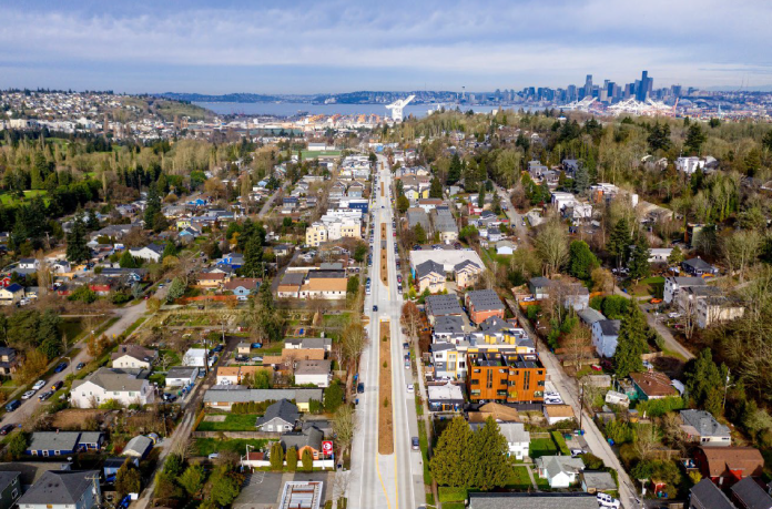 An aerial photo of a boulevard with port cranes and Elliott Bay in the distance.