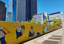 Policy Lab: Will Last Progressive in Seattle Turn On the Lights A fence with a pilot boy cartoon figure surrounding Civic Square with Seattle City Hall and the Columbia Tower skyscraper in the background.