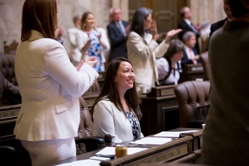 Several colleagues stand and applaud as Duerr smiles at her desk in chambers.