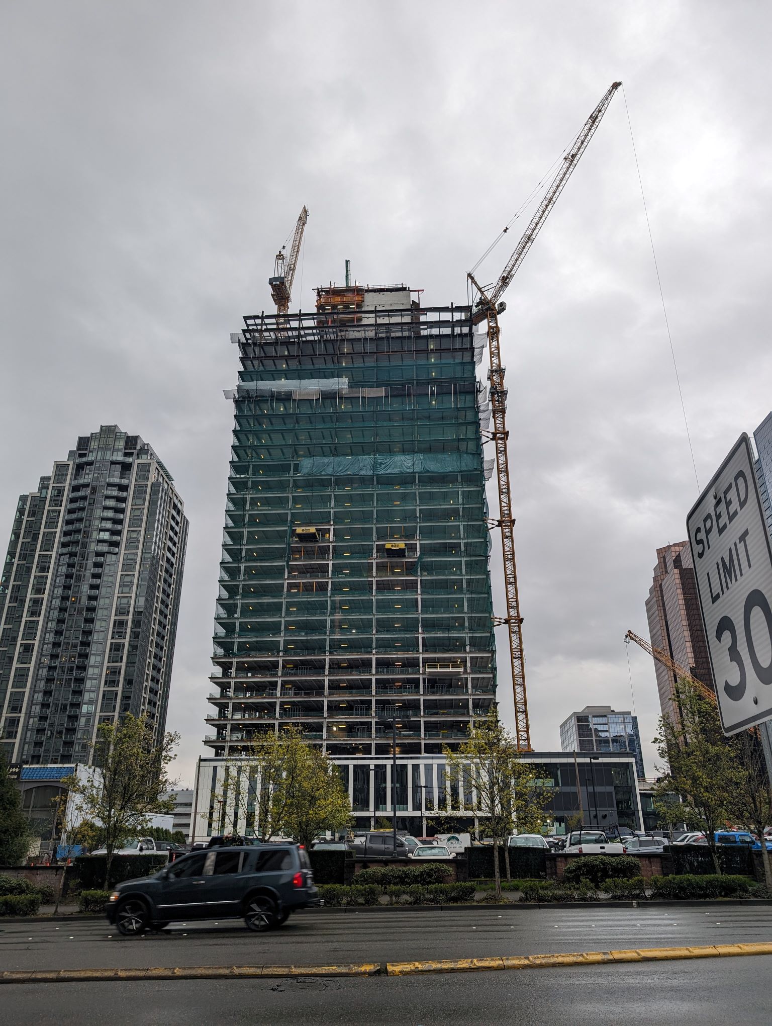 Tower under construction with two crane hovering.