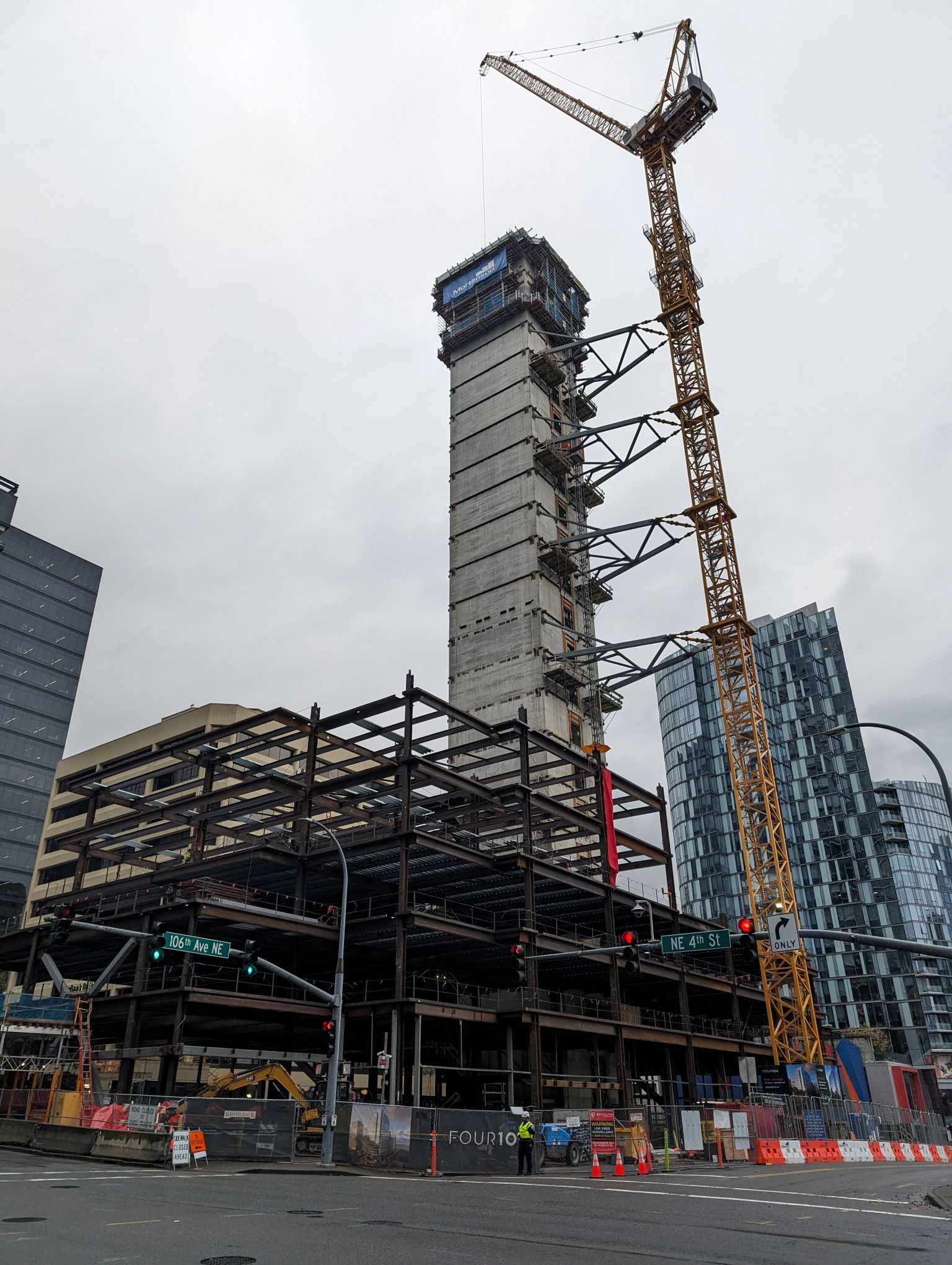 Construction with a crane rising around a elevator shaft as steel framing begin to take shape around.