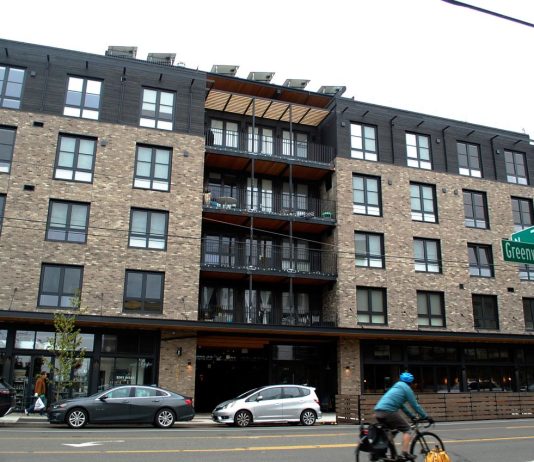 Phinney Ridge Apartment Complex Pioneers Unique Communal Model A bike whizzes by on Greenwood Avenue with a brick building in the background