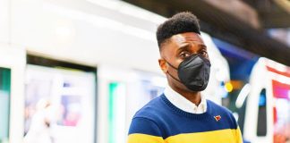 Shaun Scott Aims to Succeed Retiring Rep Chopp as Progressive Champion in Olympia Shaun Scott is a Black man with a hi-top fade and wears an N95 mask while standing in front of a Link light rail train on a station platform.