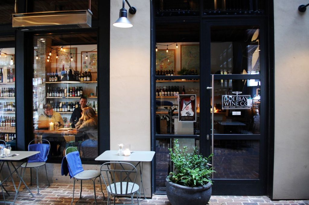 The wine shops rows of bottle's is in the background behind the outdoor patio chairs