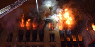 Seattle Aims to Tamp Down Vacant Building Fires Fire and smoke pours out of upper story windows of an old brick building with a fire crane seeking to control them.