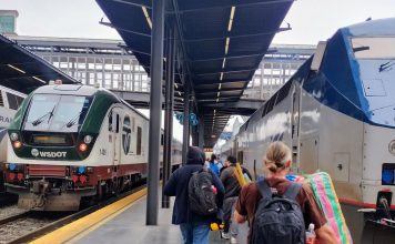 Cascadia Forges Ahead on High-Speed Rail Despite Headwinds Passengers lug their suitcases toward the train under an awning
