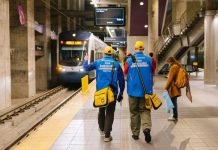 Sound Transit To Launch Platform Fare Inspection in Early June A pair of ambassadors wear blue coats and yellow hats and carry yellow bags.