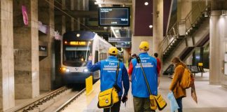 Sound Transit To Launch Platform Fare Inspection in Early June A pair of ambassadors wear blue coats and yellow hats and carry yellow bags.