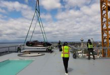 Op-Ed: Hoisting ‘Supercar’ 47 Stories Inaugurates Condo Opening, New Gilded Age A crane lowers the sport car at the edge of the hottub with the Space Needle and uptown view in the background.