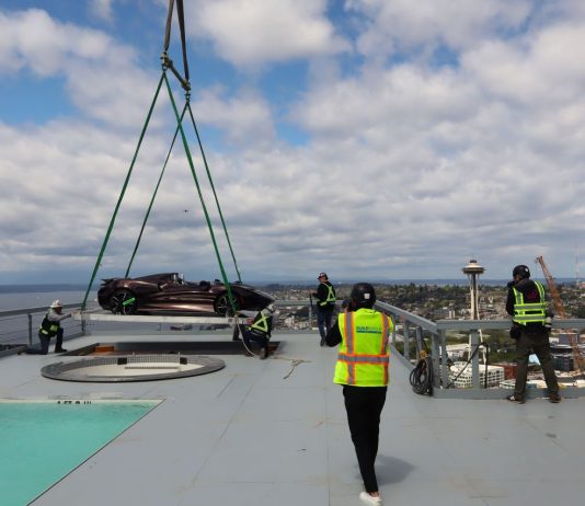 Op-Ed: Hoisting ‘Supercar’ 47 Stories Inaugurates Condo Opening, New Gilded Age A crane lowers the sport car at the edge of the hottub with the Space Needle and uptown view in the background.