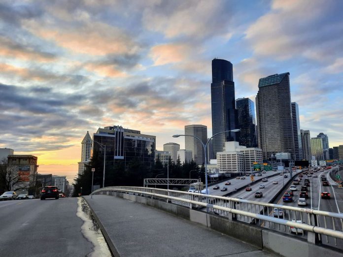 I-5 and the Seattle Skyline at sunset looking down Yesler Way to Elliott Bay with Smith Tower peeking out on the left and the car-clogged I-5 trench on the right.