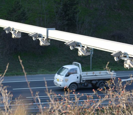 Washington Cities Question Use of License Plate Readers Citing Federal Overreach A photo shows a row of plate reader cameras over a highway with a truck going by.