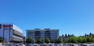 A parking lot on a hot day in Northgate, with Thornton Place behind