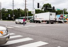 U.S. Pedestrian Deaths Rose to 40-Year High in 2022 A Black woman crosses in a crosswalk in a very wide busy road as a semi truck zooms by.