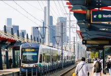 Sound Transit Launches Surveys To Plan South Seattle Link Infill Stations Two riders walked down the platform with the Seattle skyline in the distance.