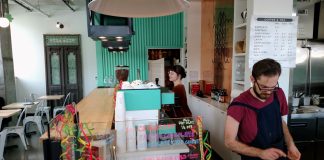 Op-Ed: Seattle Council Won’t Get Away with Gutting Minimum Wage Law Two servers behind the counter at a cafe, one at the register and another at the espresso machine.