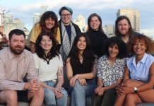 Apply to Join The Urbanist Election Committee The glass towers of the Seattle skyline peaks over the shoulders of the group.