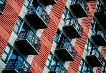 Landlords Face Price Fixing Lawsuit, but Advocates Are Looking for More A tall red residential building with balconies.