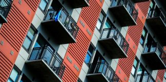 A tall red residential building with balconies.