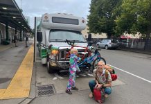 Op-Ed: Vote No on Initiative 2117 to Ensure Mobility for Washingtonians Anna Zivarts and her son smile and load a bike on the rack in front of a bus while it waits at a stop.