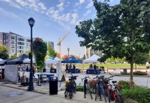 Redmond Greenlights Center Upzones, Sixplexes Citywide, Higher Affordability Requirements A central square in downtown Redmond has a row of bike parking and tents set up for a street far. Midrise apartment buildings ring the square and a construction crane adds another.