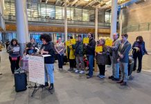 Amid Budget Showdown, Advocates Mount Defense of JumpStart Housing Funds A sign reads Resilient communities on the lectern in the lobby of city hall and people stand behind the speaker holding signs saying a protest JumpStart commitments and invest on Seattle's future.