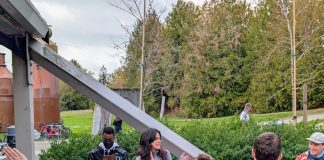 Alexis and Shaun stand in a picnic area with trees and the pipes and beams of Gas Works in the background.